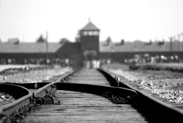 Esta fotografía en blanco y negro muestra las vías del tren que conducen a la entrada del campo de concentración y exterminio de Auschwitz-Birkenau, un lugar icónico en la memoria histórica del Holocausto. Foto de Pixabay