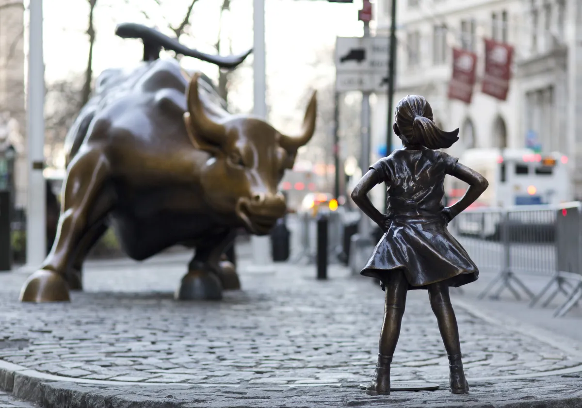 Pequeña pero firme, la Niña sin Miedo desafía al imponente toro de Wall Street. Con las manos en la cintura y la mirada al frente, simboliza la lucha por la igualdad de género en medio del poder financiero. Foto de Mark Lennihan / AP para Chicago Tribune