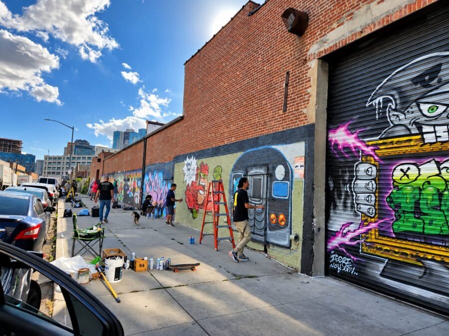 Artistas trabajan sobre una extensa pared de Nueva York, convertida en soporte para distintas intervenciones urbanas. Murales, obras encargadas y otras expresiones visuales forman parte del paisaje de la ciudad, aunque no todas responden a los mismos mecanismos de autorización, financiamiento o gestión. Foto: Olga Guerra / Archivo El Costanero.